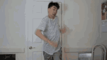 a man in a striped shirt is dancing in a room