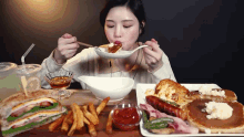 a woman is sitting at a table eating a variety of food including pancakes and french fries