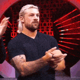 a man with blonde hair and a beard is clapping his hands .