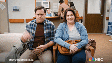 a man and a woman are sitting on a couch with a nbc logo in the background