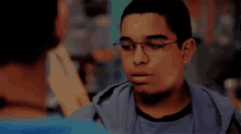 a young man wearing glasses is giving a high five to another person .