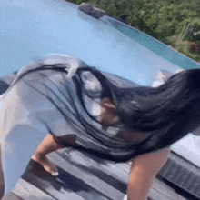 a woman with long black hair is standing in front of a swimming pool