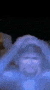 a blurry picture of a person 's face with their hands on their head .