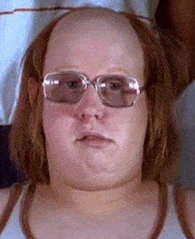 a bald man wearing glasses and a tank top .