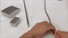 a person is playing with a string of magnets on a white surface