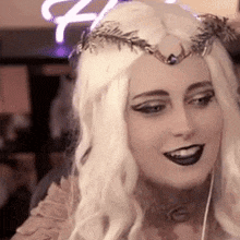 a woman wearing a white wig and a crown on her head is smiling .