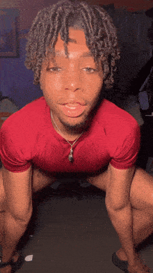 a young man in a red shirt is kneeling down