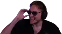 a man wearing headphones and sunglasses is smiling and making a peace sign .
