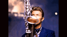 a man playing a saxophone in a blue suit and tie