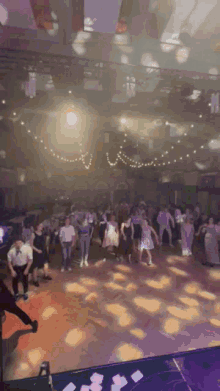 a large group of people are dancing in a ballroom