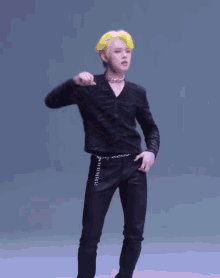 a man with yellow hair is wearing a black shirt and black jeans