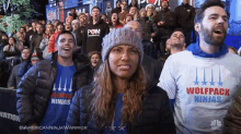 a woman wearing a wolfpack ninjas shirt stands in front of a crowd