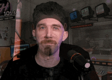 a man with a beard stands in front of a microphone in front of a sign that reads 101.1