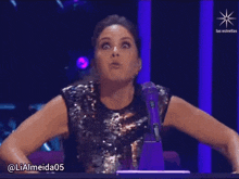 a woman with a surprised look on her face is sitting in front of a microphone with the hashtag lialmeida05 visible