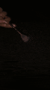 a person is holding a brush over a pile of glitter