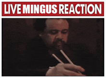 a picture of a man eating with chopsticks under a sign that says live mingus reaction