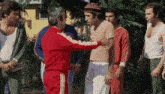 a man in a red jacket is shaking hands with a group of men