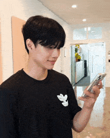 a man wearing a black adidas t-shirt holds a cell phone