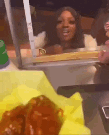 a woman is standing in front of a window talking to a man while a plate of food is on the table .