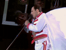 a man singing into a microphone while wearing a white and red outfit