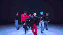 a group of young men are dancing on a stage in front of a crowd .