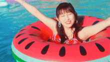a woman in a red bikini is floating in a watermelon float in a pool .