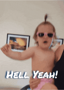 a little girl wearing sunglasses is being held by a woman and the words hell yeah are written below her