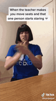a person wearing a blue adidas shirt is making a gesture with their hands