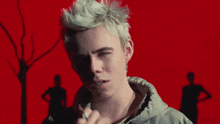 a man with white hair is standing in front of a red wall