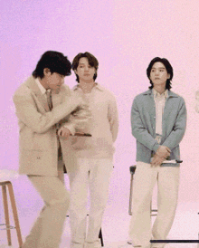a group of young men are standing in front of a pink wall