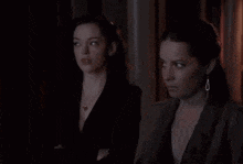 two women standing next to each other in the dark