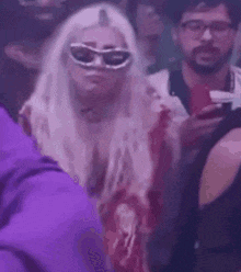 a woman in sunglasses is standing in a crowd of people .