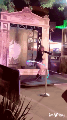 a woman stands on a hula hoop in front of a sign that says imagesplay