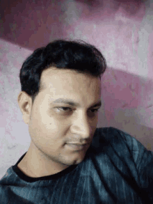 a close up of a man 's face with a pink wall behind him