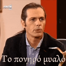 a man with a ponytail is sitting in front of a ant logo