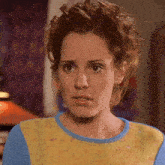 a close up of a woman 's face with a yellow and blue top