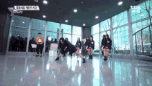 a group of girls are dancing in a room with a tbs logo on the wall