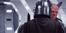 a man in a black helmet is standing next to another man in a red mask