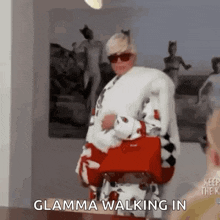 a woman is walking in a room holding a red purse .