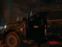 a man with a beard is standing next to a car with the words assalamualaikum on the bottom right