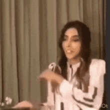 a woman is sitting at a table in front of a microphone and talking into it .