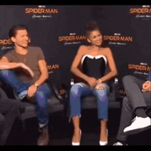 a man and a woman are sitting in front of a wall that says spider man