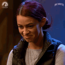 a woman with red hair is smiling in front of an ad for ink master