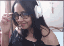 a woman wearing glasses and white headphones looks at the camera