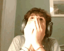 a man wearing headphones is covering his face with his hands