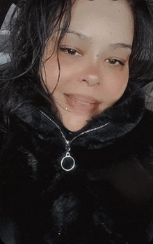 a woman wearing a black fur coat with a zipper and a ring around her neck