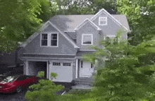 a large gray house with a red car parked in front of it .