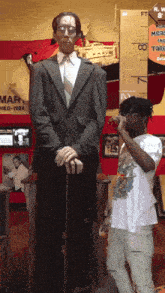 a man is standing next to a statue of a man with a cane