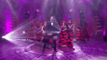 a man in a suit is dancing on a stage in front of a crowd of people