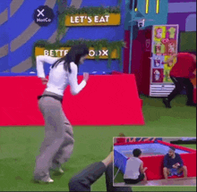 a woman is jumping in front of a sign that says let 's eat